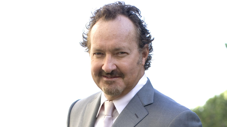 Randy Quaid in suit staring at camera